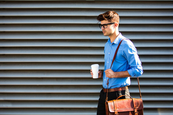 office man with glasses going to work with leather bag and cup of coffee, somewhere outside - Фото, зображення