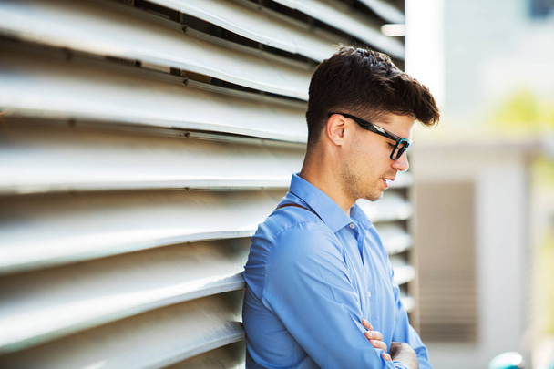 portrait of an young successful antrepreneur in blue shirt standing against a wall outside - Foto, afbeelding