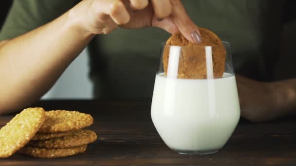 Hand putting a cookie in a glass of milk in slow motion. Food cinematic scene - Imágenes, Vídeo