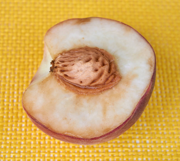 halb frischer köstlicher Pfirsich auf gelbem Hintergrund. - Foto, Bild
