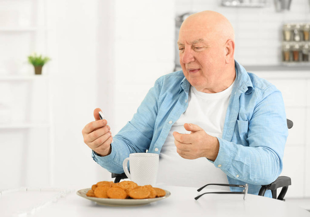 Senior man having breakfast while playing dominoes at care home - Valokuva, kuva