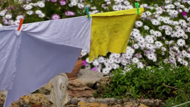 Ložní prádlo, které se suší po umytí na pozadí zahradních květin. - Záběry, video