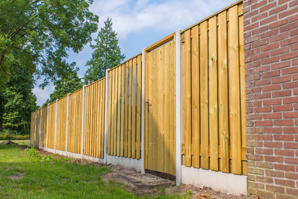 New wooden fence construction with stone wall and trees - Photo, Image
