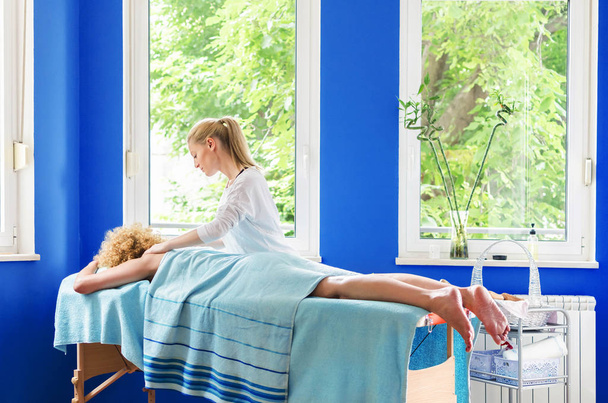 Senior patient lying on spa table at beauty spa salon and having massage of the shoulders. - Fotó, kép