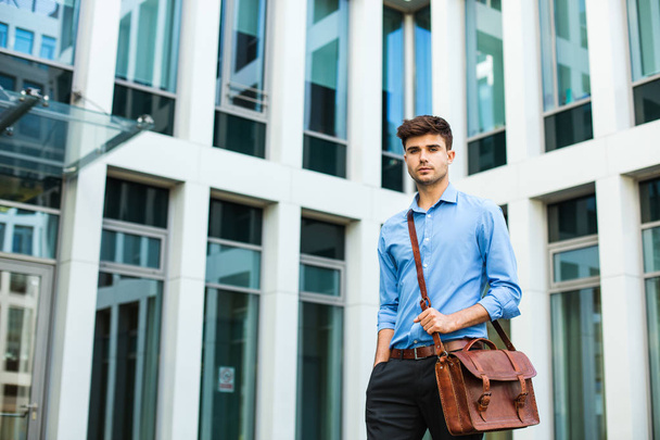 confident and successful antrepreneur, office man or corporate guy, standing with his leather bag and elegant outfit in front of an office building - Foto, imagen