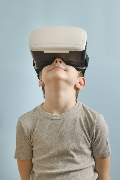 Smile boy with glasses of virtual reality looks up. Blue background - Foto, Bild