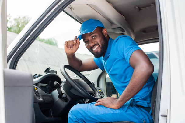 african american delivery man greeting and touching cap in car - Фото, зображення