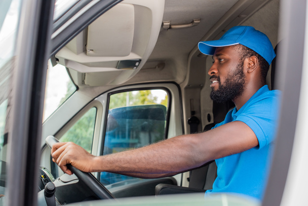 vista lateral de Africano americano entregador homem condução van
  - Foto, Imagem