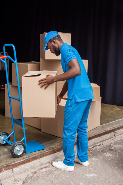 african american courier putting boxes on cart  - Foto, Imagen