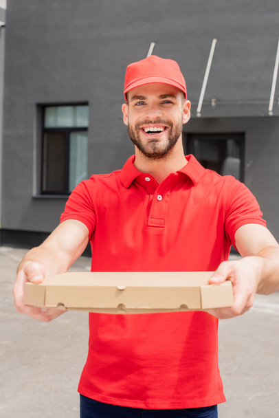 Χαμογελαστός άνθρωπος Καυκάσιος παράδοσης που κρατά κουτί με πίτσα και βλέπουν τα φωτογραφικών μηχανών - Φωτογραφία, εικόνα
