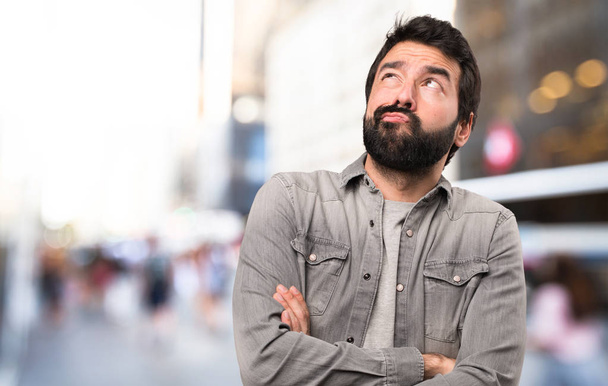 Handsome man with beard having doubts at outdoor - Photo, Image
