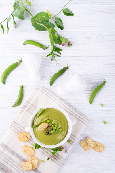 Verano claro deliciosa sopa de crema de guisantes verdes servido con semillas de calabaza, croutons sobre fondo blanco. plano laico
. - Foto, imagen