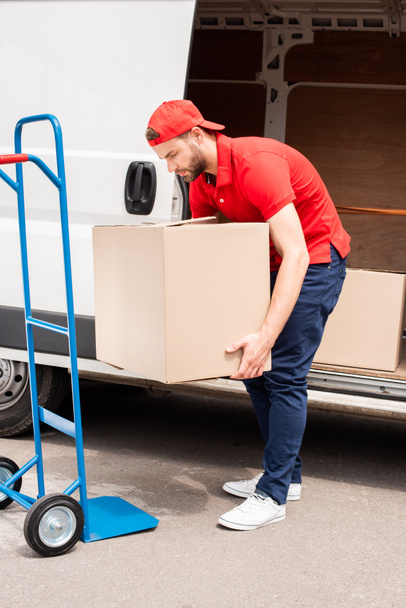 young delivery man discharging cardboard boxes from van - Zdjęcie, obraz