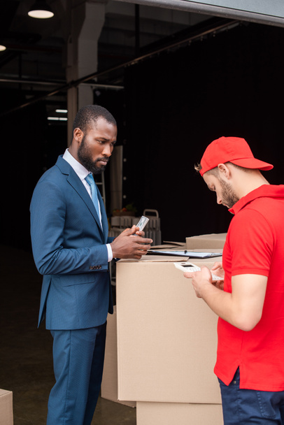 african american client with money and caucasian delivery man with calculator - 写真・画像
