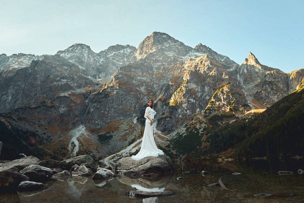 A beautiful bride walks near a lake in the mountains - Foto, imagen