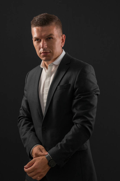 Young businessman standing on dark background - Φωτογραφία, εικόνα