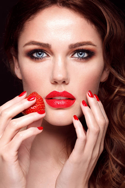 Όμορφο νεαρό θηλυκό μοντέλο με κόκκινα χείλη και μανικιούρ κρατώντας φράουλα. Στούντιο μόδας πορτρέτο  - Φωτογραφία, εικόνα