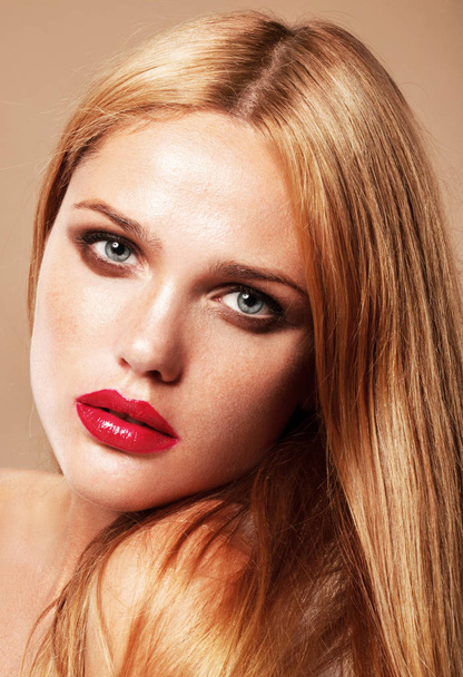 close up fashion portrait of tanned blonde model with red lips posing on beige background - Zdjęcie, obraz