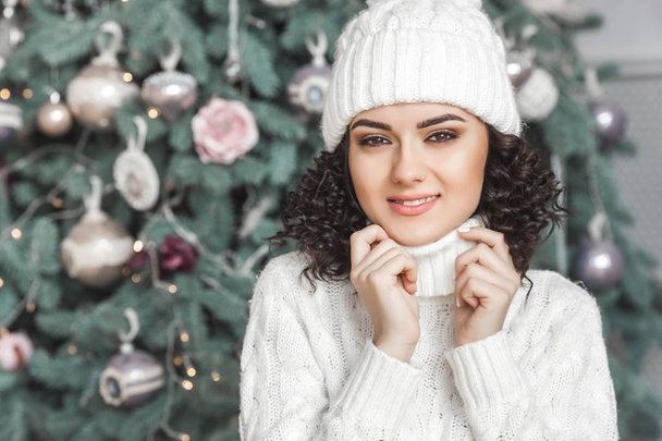 Fiatal gyönyörű lány mosolyogva kamera karácsonyfa közelében. Vidám szép nő - Fotó, kép