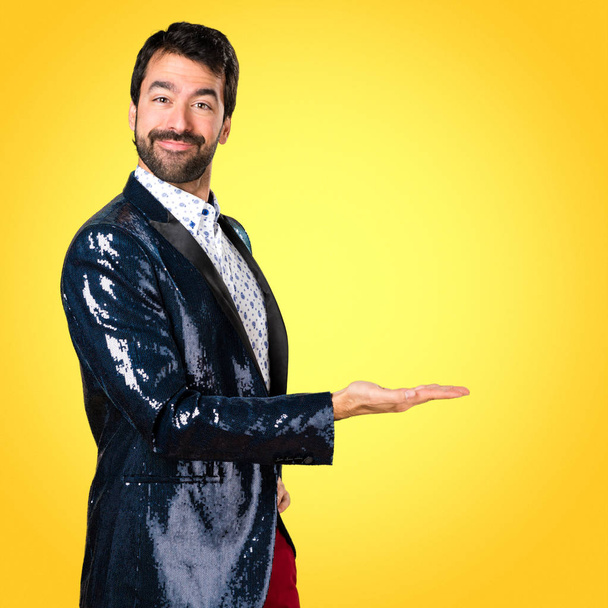Man met jasje presenteren iets op kleurrijke achtergrond - Foto, afbeelding
