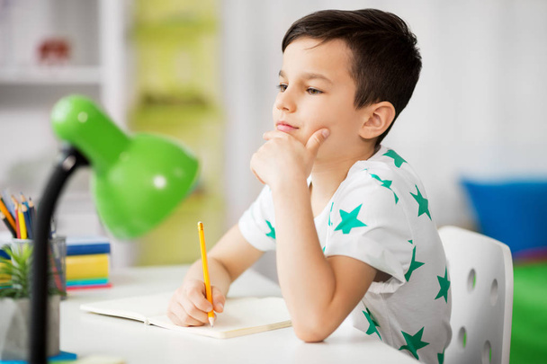 little boy writing to notebook at home - Foto, Bild