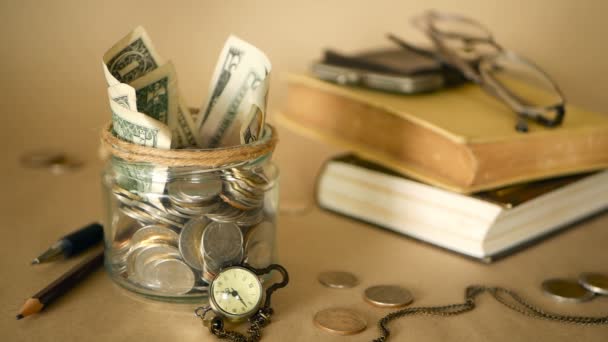 Books with glass penny jar filled with coins and banknotes. Tuition or education financing concept. Scholarship money. - Footage, Video