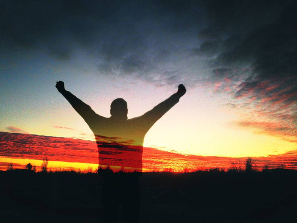 Σιλουέτα του ανθρώπου στο ηλιοβασίλεμα ύψωσε τα χέρια του επάνω - Φωτογραφία, εικόνα