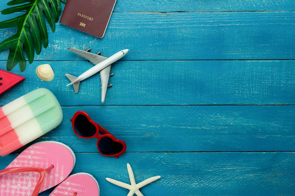 Tablo üstten görünüm moda yaz tatil arka planda seyahat hava görüntüsü. Düz yatıyordu aksesuarları seyahat için giyim. Pasaport ve modern mavi ahşap uçak ile güneş gözlüğü. Alan içeriği için. - Fotoğraf, Görsel