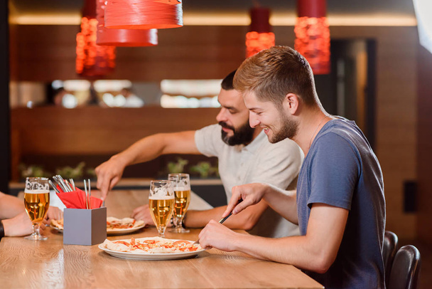 Two friends eating pizza using knife and fork. - Fotografie, Obrázek