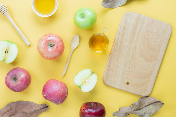 Table top view aerial image of decorations Jewish holiday Rosh Hashana background concept.Flat lay of variety apple & honey bee with wood plank on modern rustic yellow paper.Free space for creative. - Photo, Image