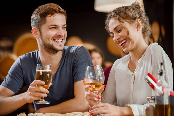 Beautiful couple holding glasses of white wine and beer in restaurant. - Foto, Bild