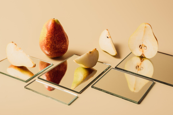yellow pears reflecting in mirrors on beige tabletop - Foto, Imagem