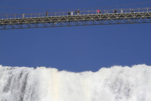 People on a walking bridge above Montmorency Falls in Quebec - Photo, Image