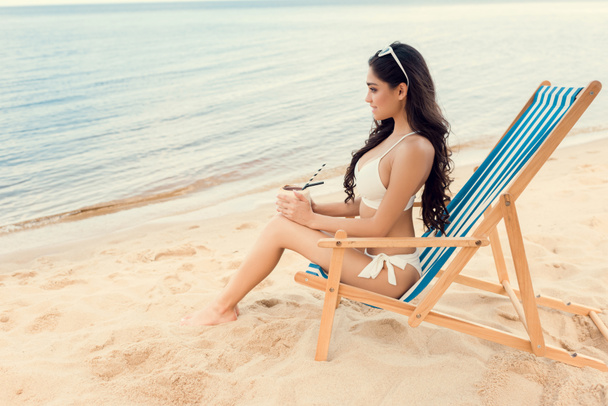 hermosa joven con bebida de coco verde en la playa de arena
 - Foto, imagen