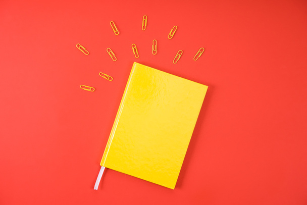 κάτοψη του κίτρινο σημειωματάριο με συνδετήρες στο κόκκινο - Φωτογραφία, εικόνα