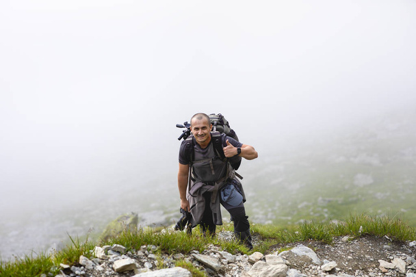 Fotógrafo com mochila e câmera caminhando em uma trilha de montanha
 - Foto, Imagem