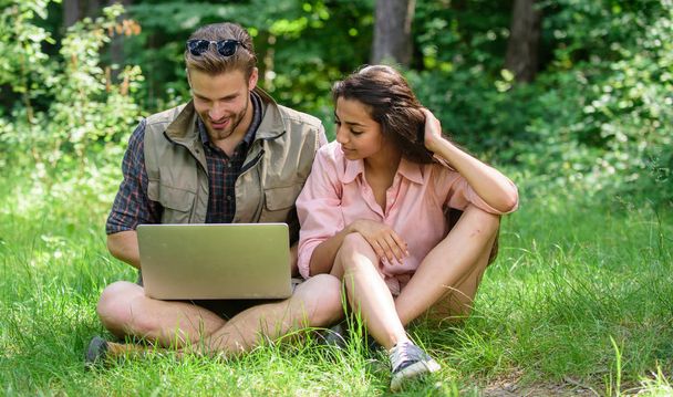 Couple youth spend leisure outdoors with laptop. Modern technologies give opportunity to be online and work in any environment conditions. Man and girl looking at laptop screen. Closer to nature. - Photo, Image