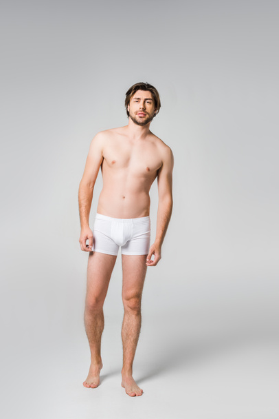 jeune homme en sous-vêtements blancs posant sur fond gris
 - Photo, image
