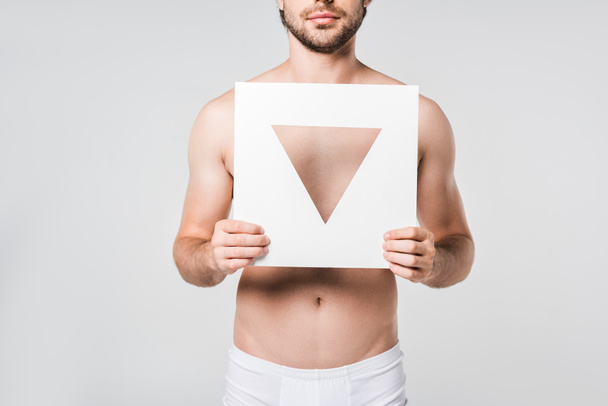 cropped shot of man in underwear holding white paper triangle figure isolated on grey - Fotografie, Obrázek