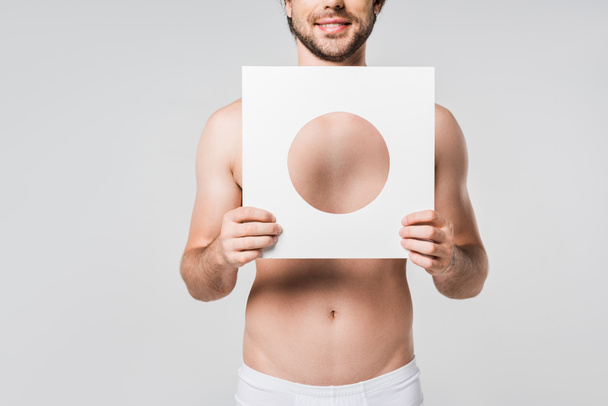 cropped shot of smiling man in underwear holding white paper circle figure isolated on grey - Fotó, kép