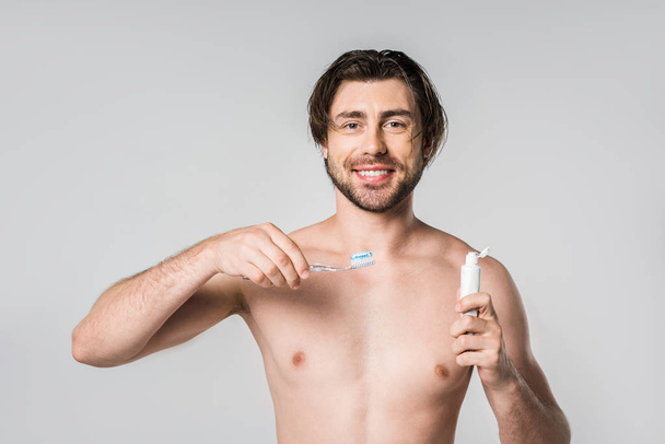 ritratto di uomo senza camicia sorridente con spazzolino e dentifricio isolato su grigio
 - Foto, immagini