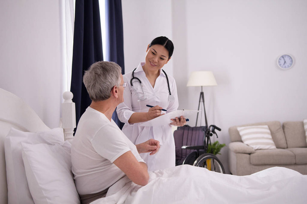 Nurse checking up on patient in bed. - Photo, Image