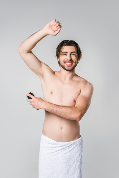 portrait of smiling man in white towel with male deodorant isolated on grey - Φωτογραφία, εικόνα