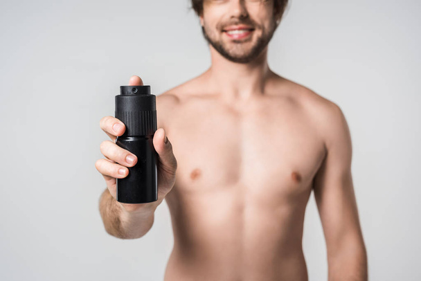 selective focus of shirtless man with male deodorant isolated on grey - Photo, Image