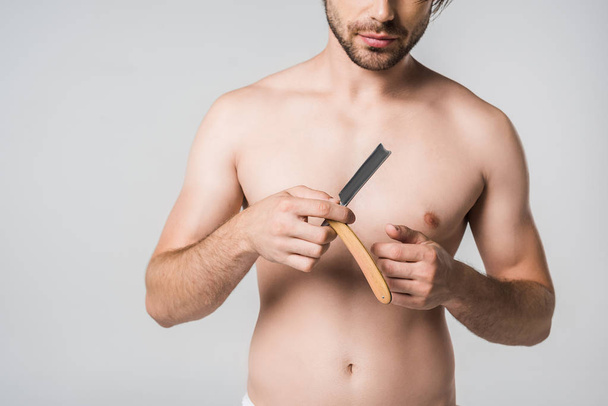 visão parcial do homem sem camisa com navalha reta em mãos isoladas em cinza
 - Foto, Imagem
