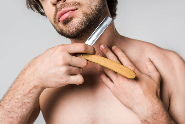グレーに分離されてひげを剃る手ストレートかみそりを持つ男のクロップ撮影 - 写真・画像