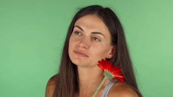 Preciosa mujer sonriendo mirando hacia otro lado soñando sosteniendo una flor
 - Imágenes, Vídeo