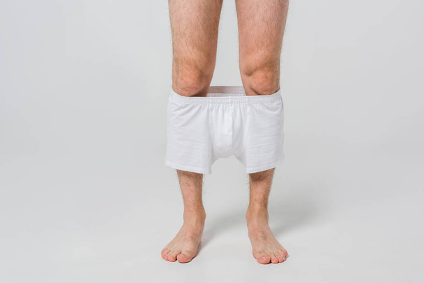 cropped shot of man with slipped down white underwear on grey backdrop - Foto, Imagem