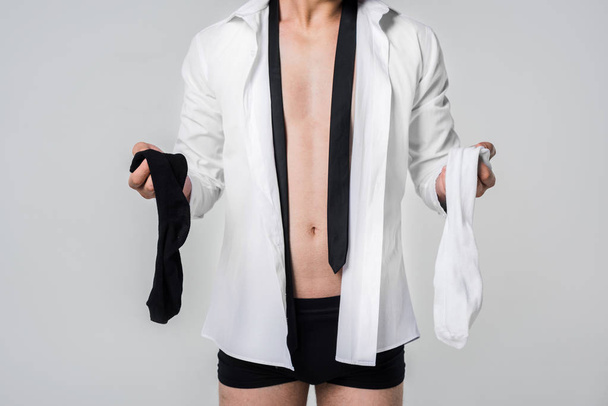 cropped shot of man in shirt and underwear holding black and white socks isolated on grey - Foto, Imagen