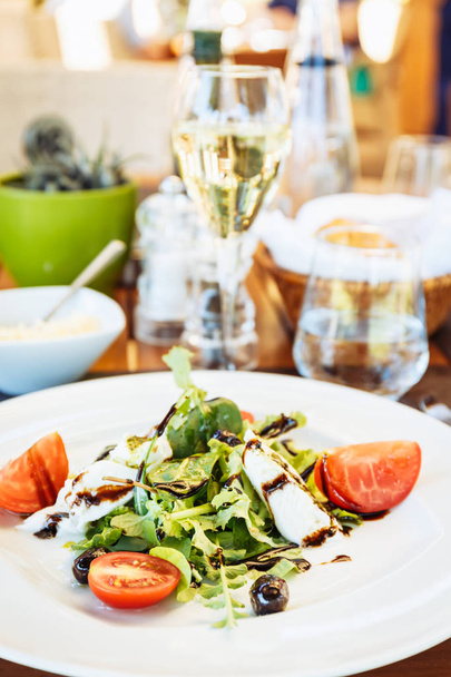 Caprese salad at the table. Outdoor Italian restaurant terrace. Concept of summer authentic meal. Vertical - Fotó, kép